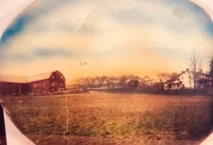 Vintage farmhouse and red barn across field