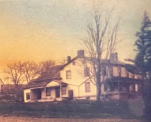 Sunset-lit vintage farmhouse with wraparound porch