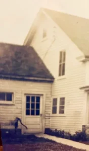 Vintage white clapboard house with hand pump