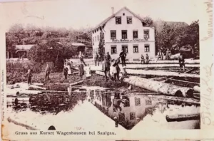 Historic riverside sawmill with logs and reflection