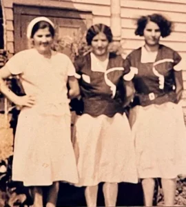 Three women in vintage dresses standing together
