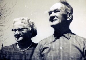 Elderly couple smiling outdoors in vintage photo