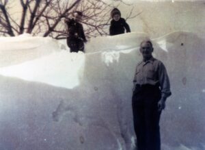 Man and children beside towering snowbank