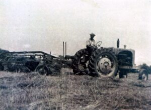 Vintage farmer driving tractor across harvested field