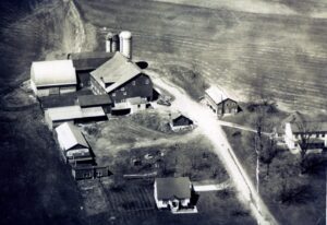 Aerial view of farmhouse and barns with silos