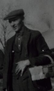 Man in flat cap carrying parcel box