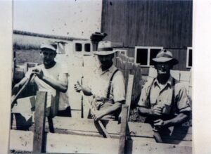 Three men building concrete block wall