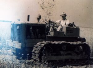 Vintage farmer driving crawler tractor in field