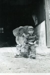 Two smiling children in barn doorway