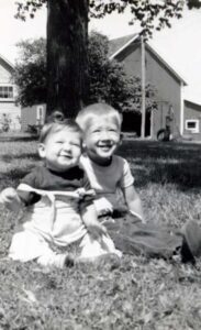 Two young children smiling on grass