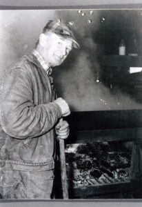Smiling man stoking smoky barbecue pit