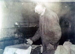 Man tending animals in a dim rustic barn