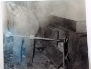 Worker stoking a large coal-fired furnace