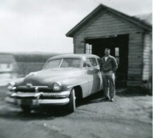 Man leaning on vintage car by garage