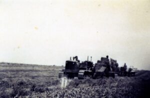 Tracked tractor towing hay-filled trailer across field