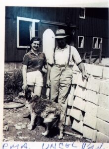 Smiling couple with dog by cinderblock wall