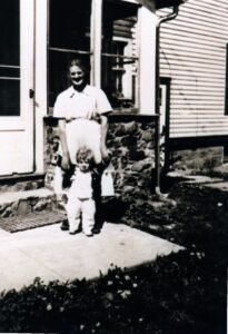 Vintage woman and toddler standing outside house