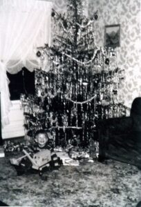 Smiling child by tinsel-covered Christmas tree