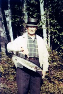 Elderly man holding large fish in woods