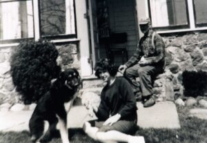 Vintage woman petting dog, man sitting on porch