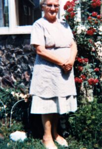 Smiling elderly woman standing beside red roses