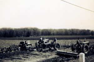 Three vintage tractors plowing a field