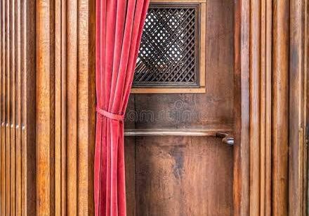 Wooden church confessional with red curtain
