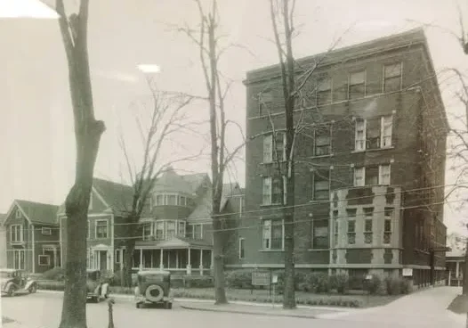 Historic brick apartment building with vintage cars