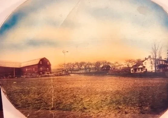 Vintage farmhouse and red barn across field