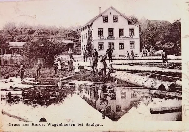 Historic riverside sawmill with logs and reflection