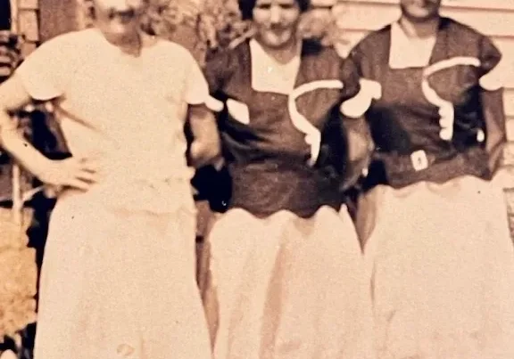 Three women in vintage dresses standing together