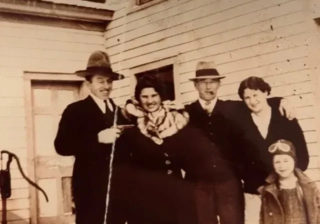 Vintage family portrait outside snowy wooden house
