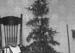 Vintage sparse Christmas tree beside wooden chair